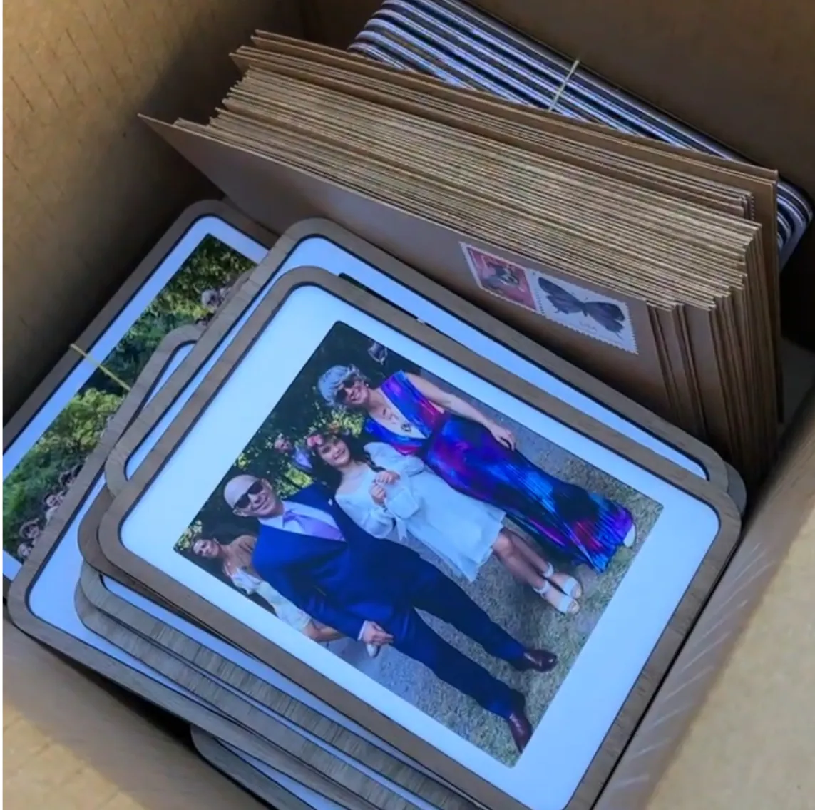 A box of Pop-up Frames and envelopes, one holding a photo of wedding guests